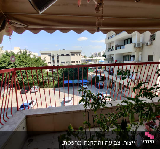 מעקה ברזל אדום במרפסת עם צמחים